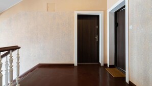 A hallway with a wooden floor, a dark door, and a white railing.