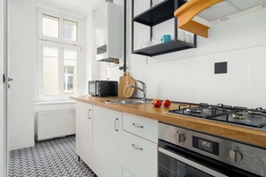 Une cuisine moderne dotée d’un plan de travail en bois, d’appareils électroménagers en acier inoxydable et de meubles blancs.
