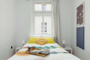 A bedroom with a bed, two bedside tables, a window with curtains, and wall art. - Cozy Apartment in the City Center | Near the Old Market Square (Poznań)