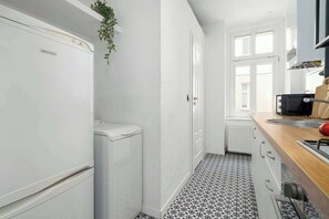 Une cuisine de taille réduite, équipée d’un réfrigérateur, d’un évier et d’une fenêtre.
