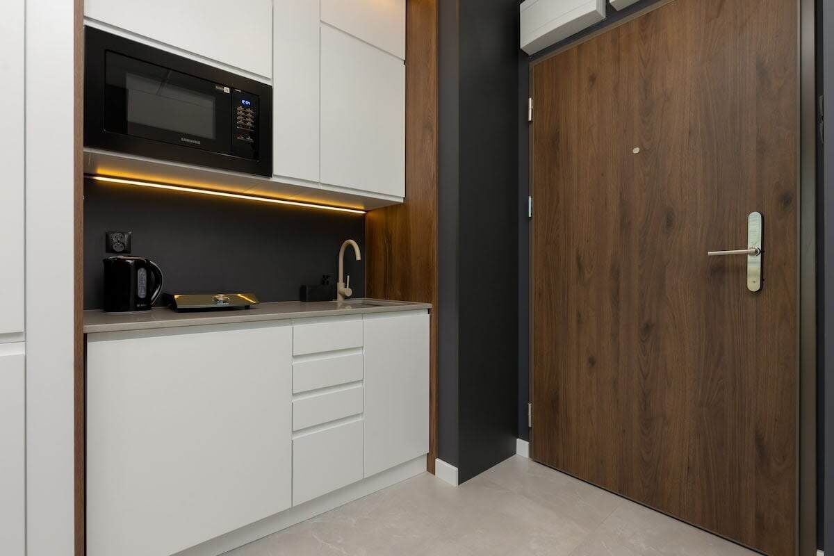A modern kitchen with white cabinets, a black microwave, and a coffee maker.