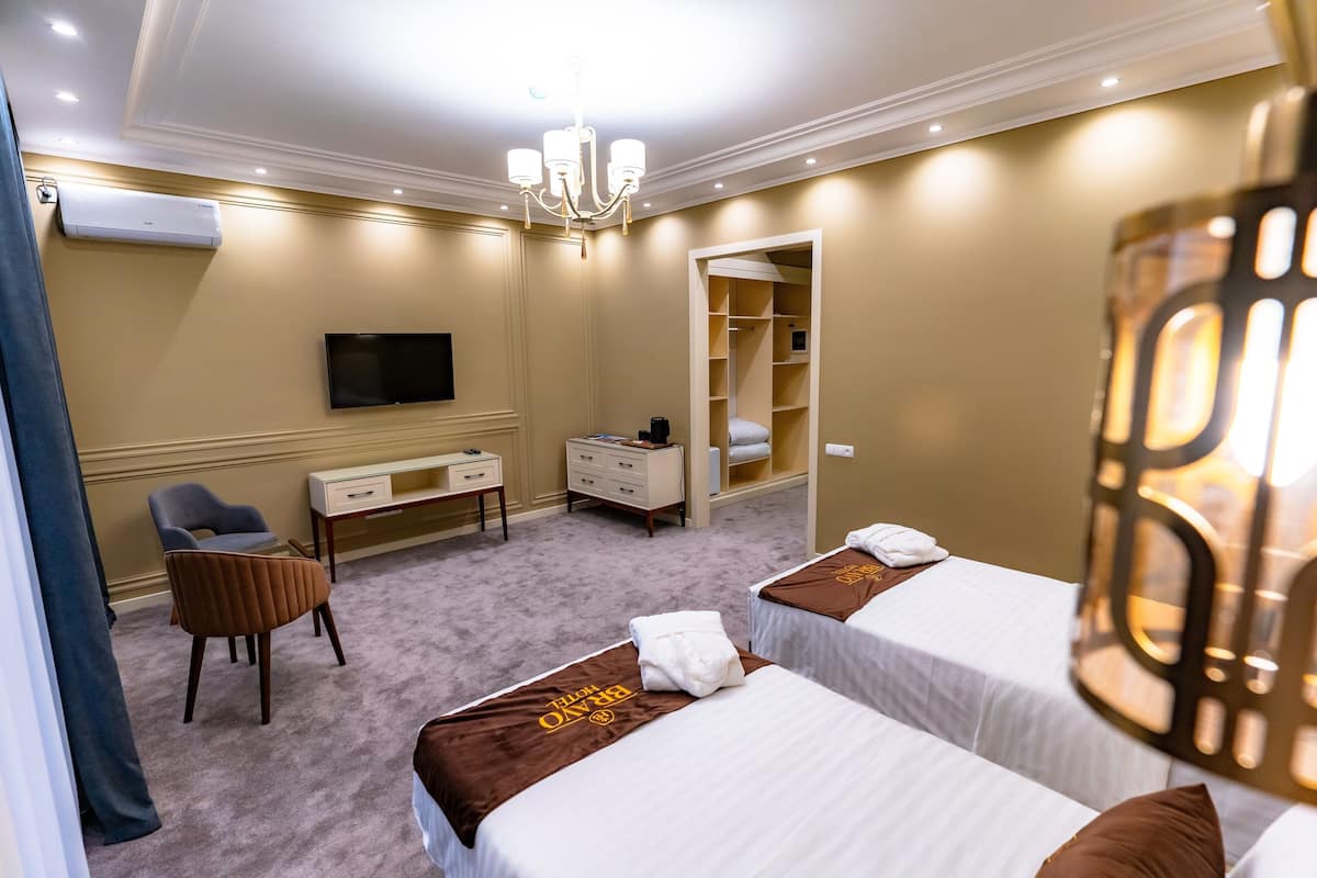 A hotel room with two beds, a TV, a desk, a chair, and a wardrobe.