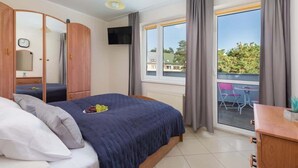 Une chambre à coucher avec un lit, une télévision, une fenêtre avec des rideaux et une vue sur l’extérieur.