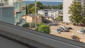 Un immeuble d’appartements moderne doté de balcons, d’un parking et offrant une vue sur la mer.
