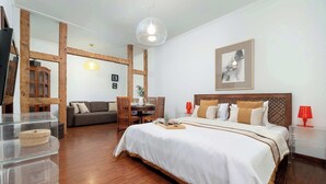 Une chambre d’hôtel avec un grand lit, des poutres apparentes, une table à manger et un canapé.