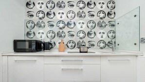 Une cuisine moderne équipée d’un four à micro-ondes, d’un grille-pain et d’une bouilloire sur le plan de travail, et d’une porte de douche en verre.