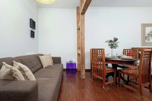 A living room with a brown sofa, a wooden dining table set for four, and a purple side table.