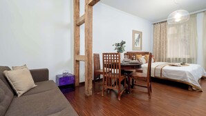 Une pièce comprenant une table à manger en bois, un canapé, un lit et une structure en poutres apparentes.