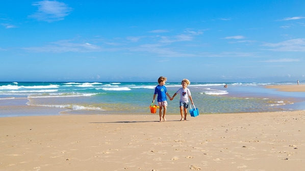 Children enjoy a leisurely walk along the beach, where the ocean waves gently crash onto the shore.
