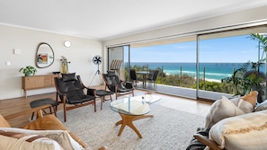 Relax in a spacious living room with a large glass table, sofa, and armchairs, offering a comfortable seating area.
