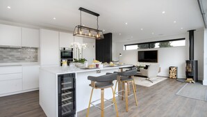 Una cocina moderna con una isla central, taburetes de bar y un horno empotrado.