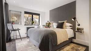Un dormitorio moderno con una cama grande, un escritorio y una ventana con vistas a las montañas.