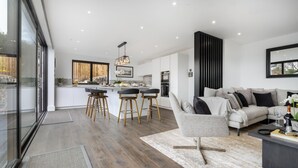 Una cocina moderna con una isla central, taburetes de bar y una zona de comedor.