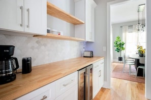 Una cocina moderna con armarios blancos, encimera de madera y un tostador.