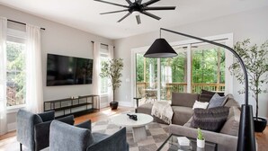 A modern living room with a sofa, armchairs, a coffee table, and a TV. - Aquarius Rising (Atlanta)