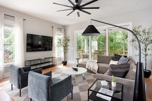 Una sala de estar moderna con un sofá, sillones, una mesa de centro y un televisor.