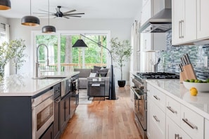 Una cocina moderna con una isla central, electrodomésticos integrados y un amplio ventanal con vistas al exterior.