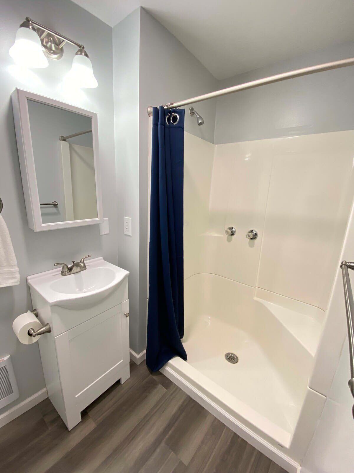 A modern bathroom with a white sink, mirror, and shower.
