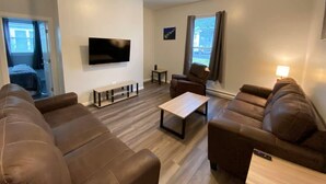 Ein modernes Wohnzimmer mit braunen Ledersofas, einem Flachbildfernseher, einem Couchtisch und einer Bank.