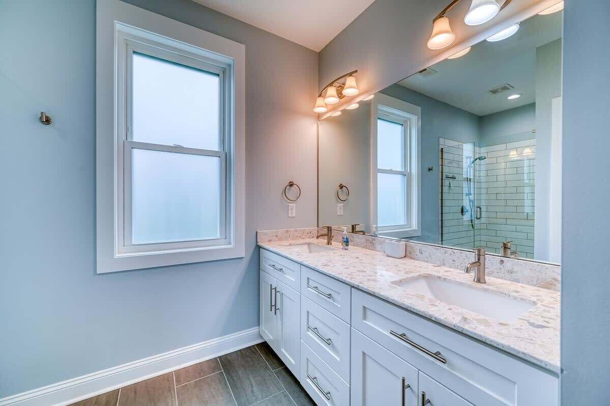 Un baño moderno con dos lavamanos, un espejo grande y zona de ducha.