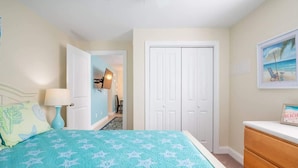 A bedroom with a bed, a dresser, a door, and a painting on the wall.