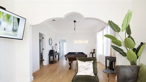 A spacious living room with a pool table, a green armchair, and a large plant. - Beautiful 3 bedroom home w/Patio, BBQ Grill & Fire table. Steps from 7th Ave.  (Tampa)