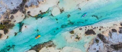 An aerial view of a turquoise river with kayaks.