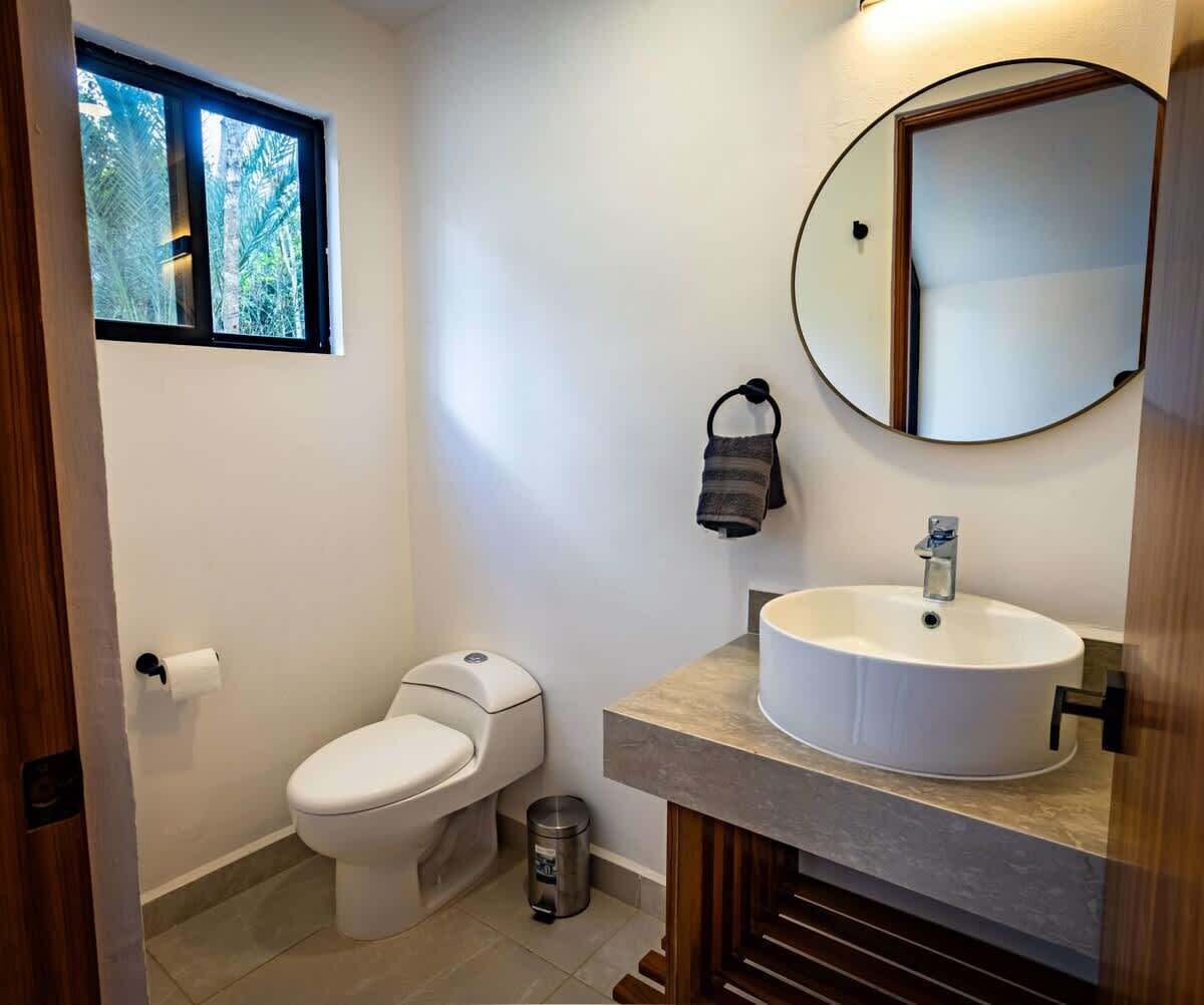 Ein Badezimmer mit Toilette, Waschbecken, Spiegel und Fenster.
