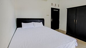 A room with a bed, a black wardrobe, and a door. - OYO Life 92754 Kost Griya Perdana (Mataram)