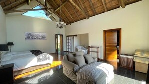 Un dormitorio con dos camas, techo de madera, candelabro, bañera y puerta de madera.