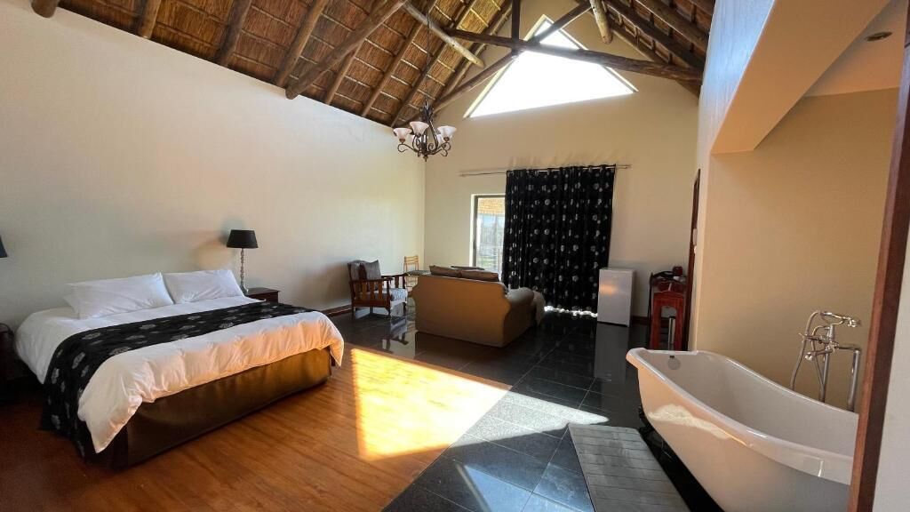 Une chambre avec un lit, un canapé, une baignoire et un coin repas.