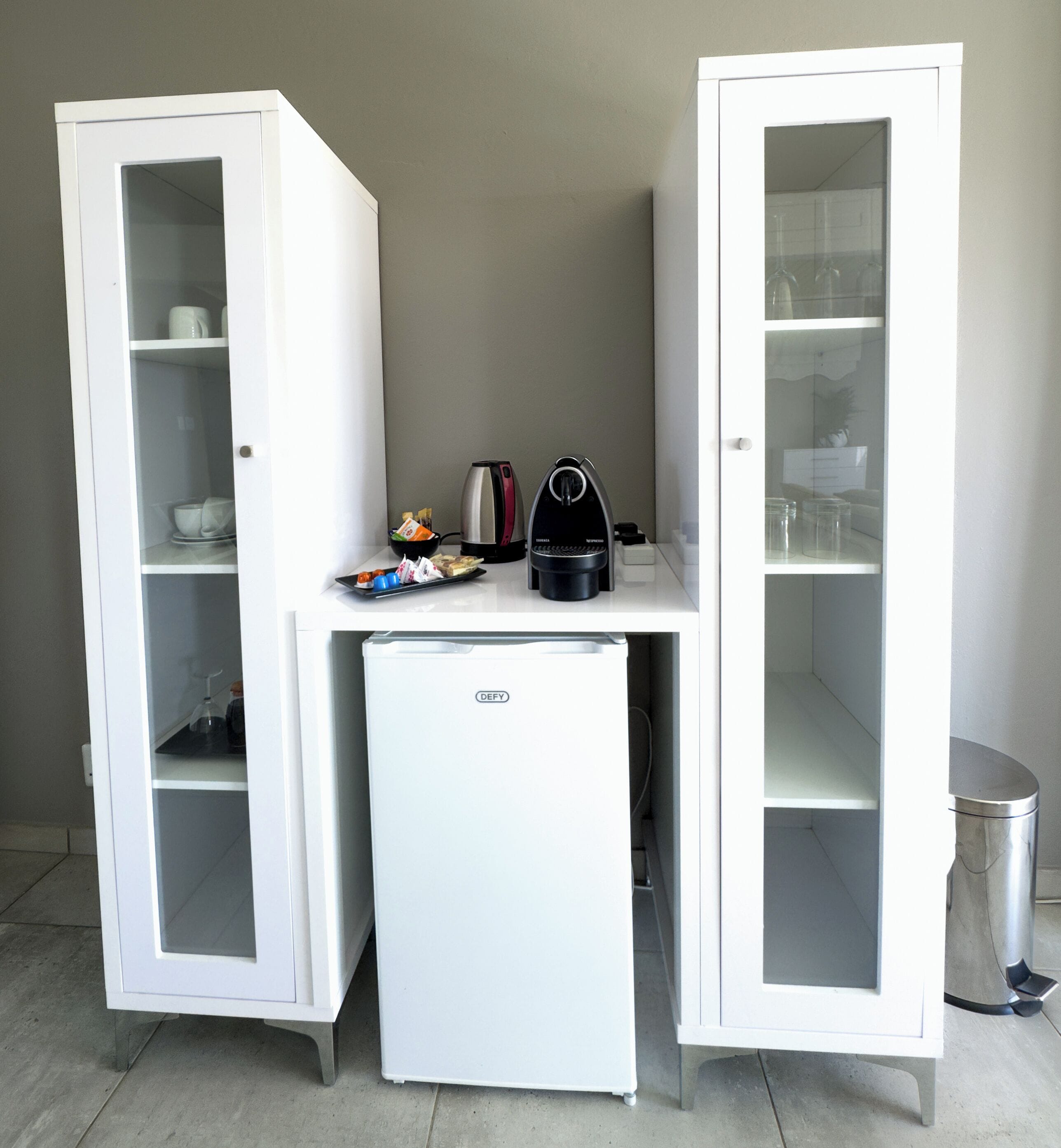 A kitchenette with a white refrigerator, a coffee maker, and a small sink.