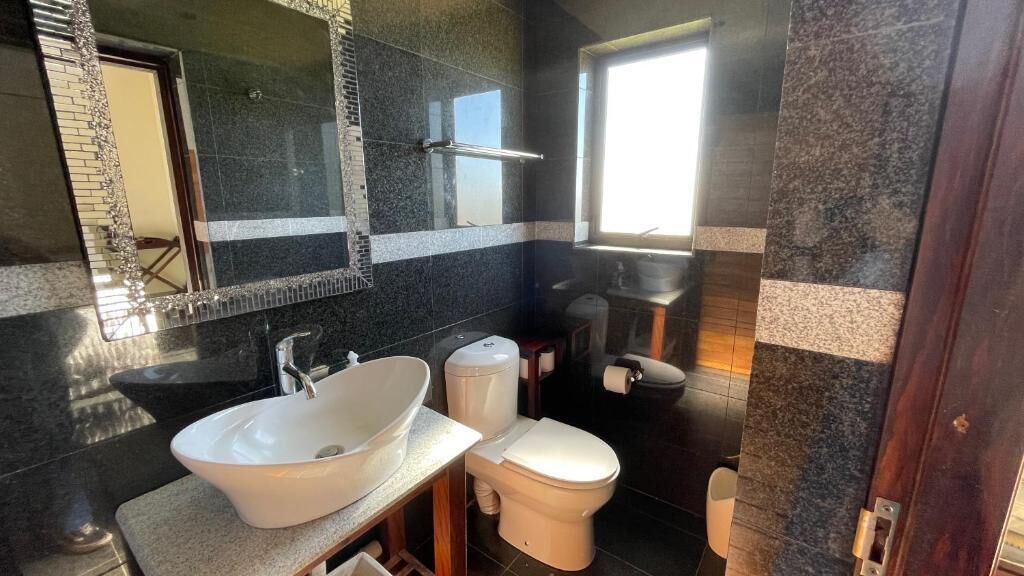 A bathroom with a white sink, a toilet, and a mirror.