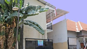 A building with a gated entrance, a balcony, and a tiled roof. - OYO Life 92925 Kost Bu Mala 2 Syariah (Sukorejo)
