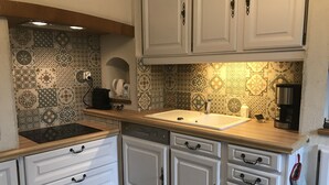 A kitchen with white cabinets, a wooden countertop, and patterned backsplash tiles.
