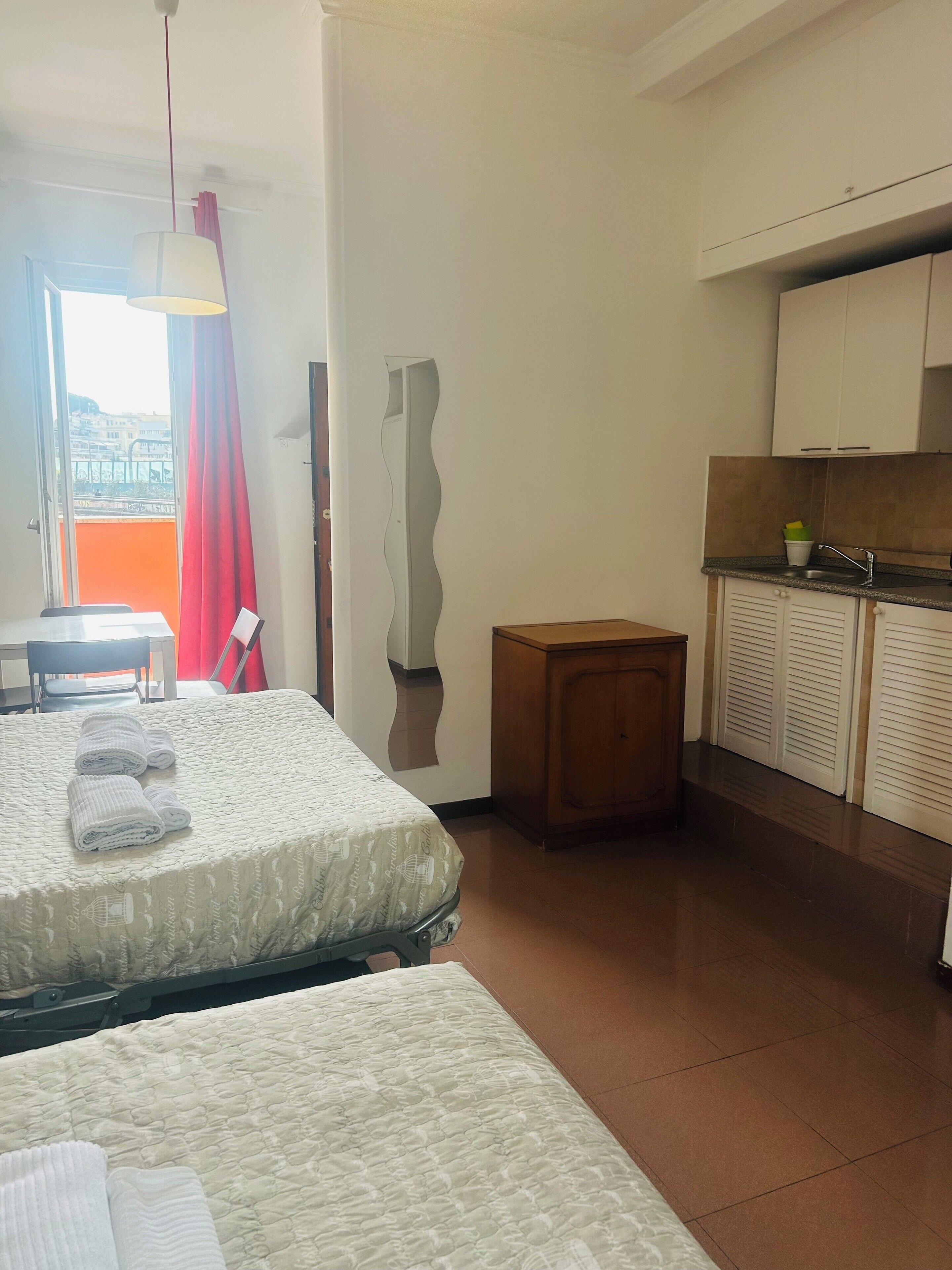 Habitación de hotel con dos camas, una kitchenette pequeña y vista a la ciudad.