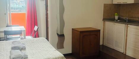 Habitación de hotel con dos camas, una kitchenette pequeña y vista a la ciudad.