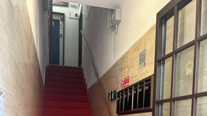 Una escala amb alfàbega vermella que condueix a una porta amb el logotip 'Hotel M'.