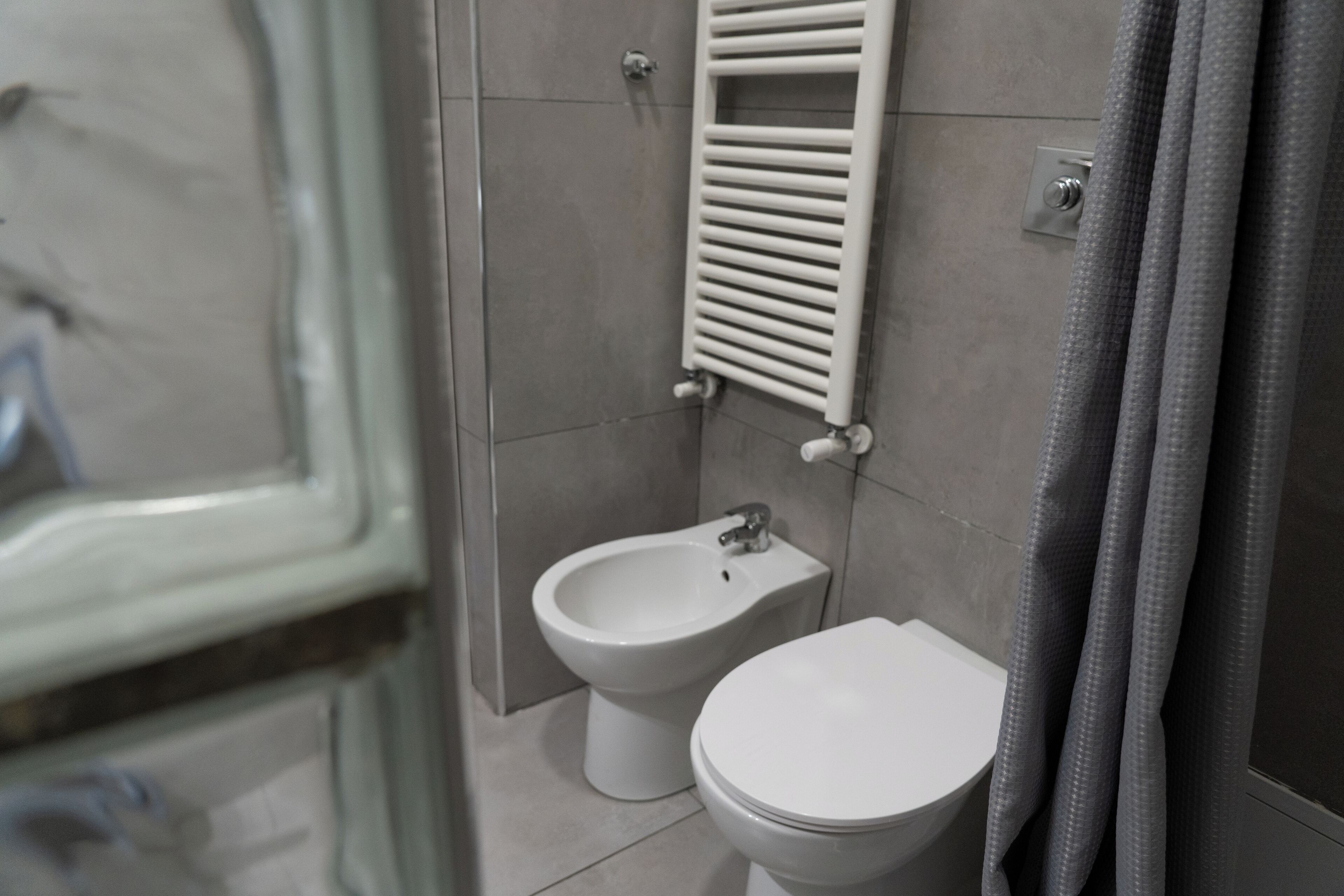 Un baño con bidé, inodoro y perchero para toallas.