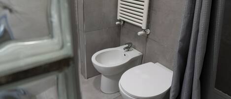 Un baño con bidé, inodoro y perchero para toallas.