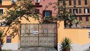 Una entrada tancada amb una reixa metàl·lica, una planta en test i un edifici amb nombroses finestres i balcons.