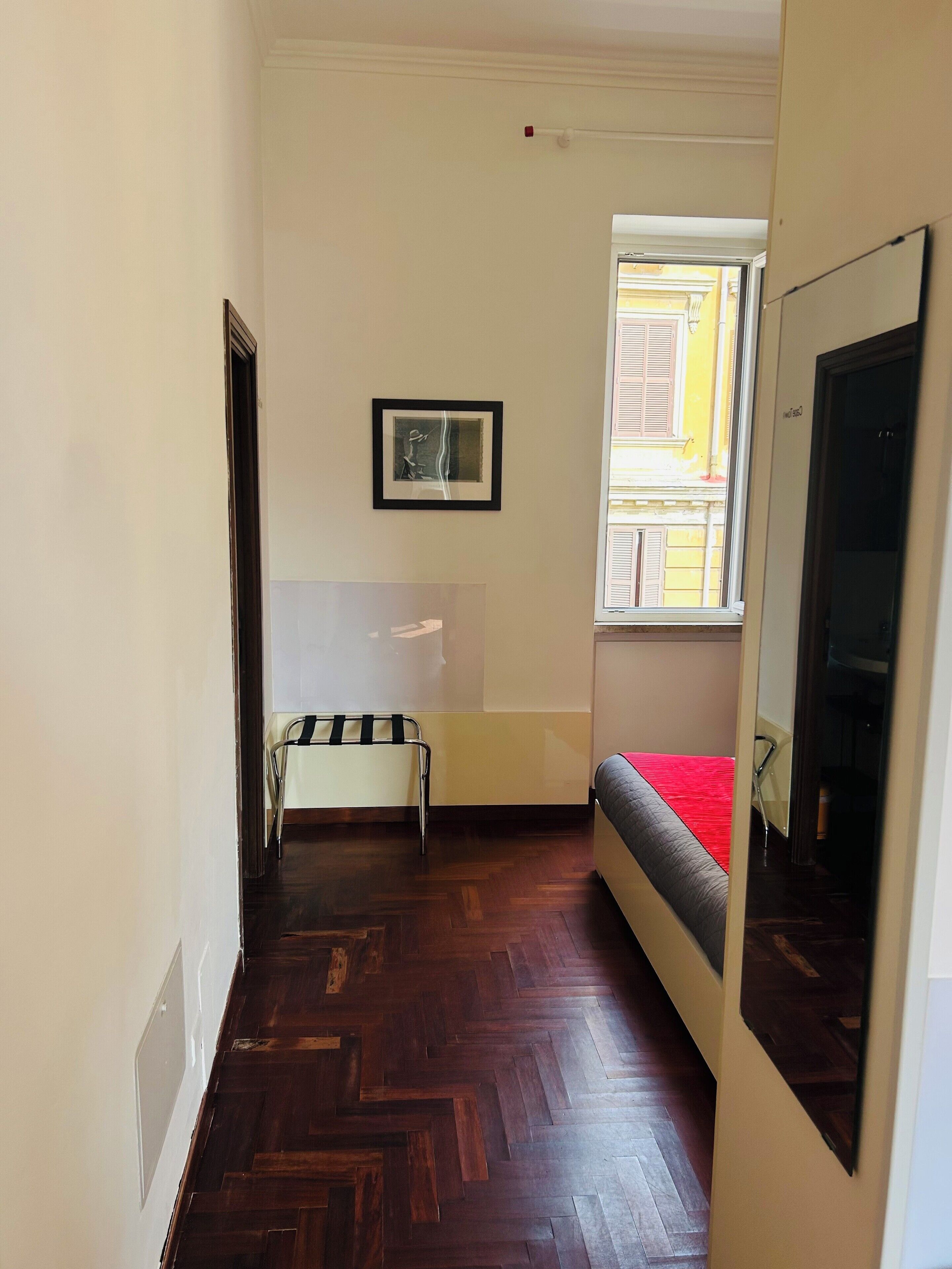 Una stanza con un letto, una sedia, un tavolino e una finestra con persiane.