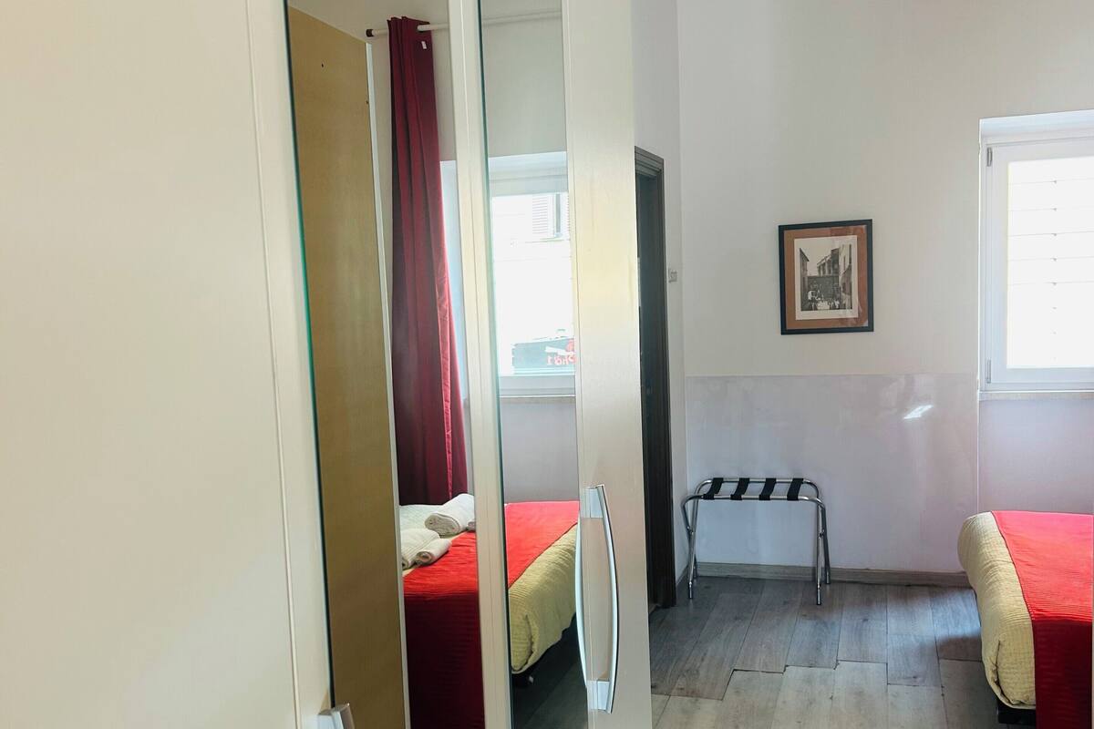 A hotel room with a bed, a chair, a small table, a window, and a picture on the wall.