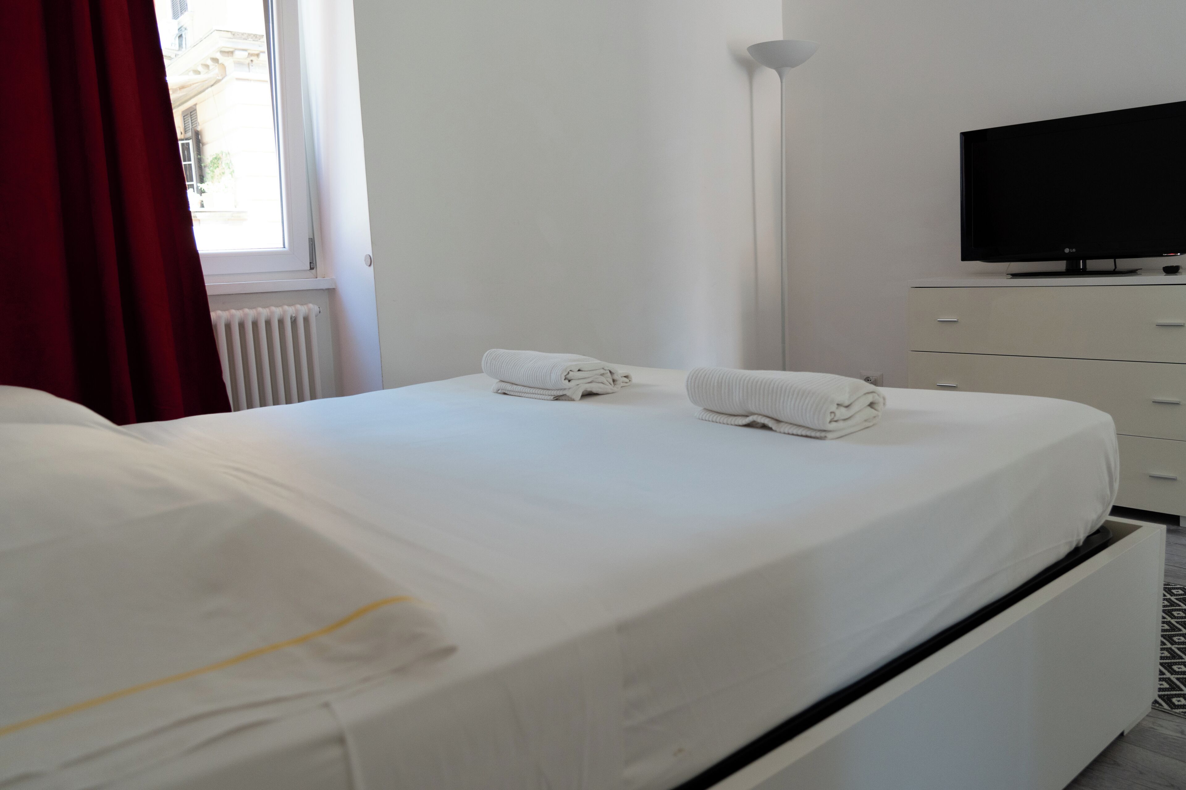 A hotel room with a bed, a TV, and a dresser.