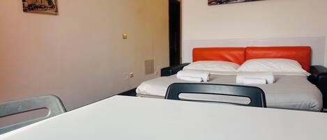 Et hotelværelse med en seng, et skrivebord og to billeder på væggene.