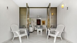 Une pièce avec deux chaises en plastique blanches, un canapé blanc et une petite table blanche.