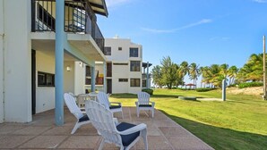 Un bâtiment doté d’un patio comprenant un espace extérieur aménagé avec des sièges et offrant une vue sur une pelouse bien entretenue et des palmiers.
