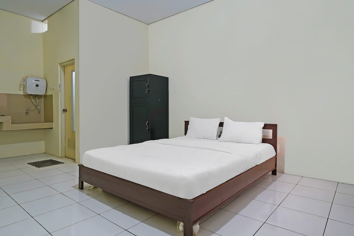 Un dormitorio con cama, armario y dispensador de gel hidroalcohólico en la pared.