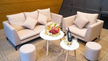A modern living room with two sofas, a small round table with a decorative centerpiece, and two ottomans.