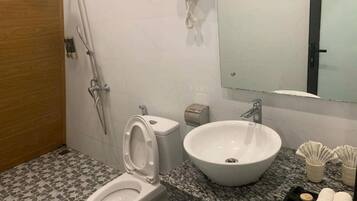 A bathroom with a toilet, bidet, sink, and a hairdryer mounted on the wall.